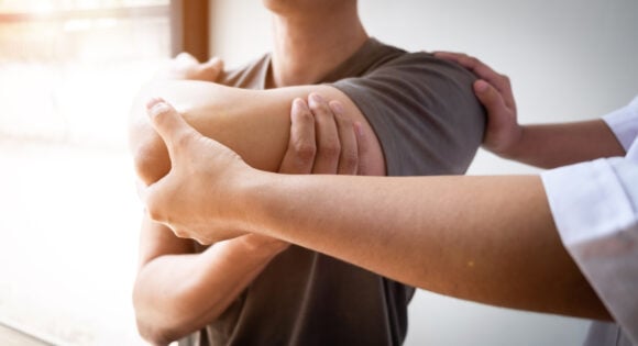 Therapist treating a male injured by rotator cuff