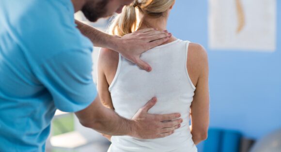 Male physical therapist giving back massage to female patient