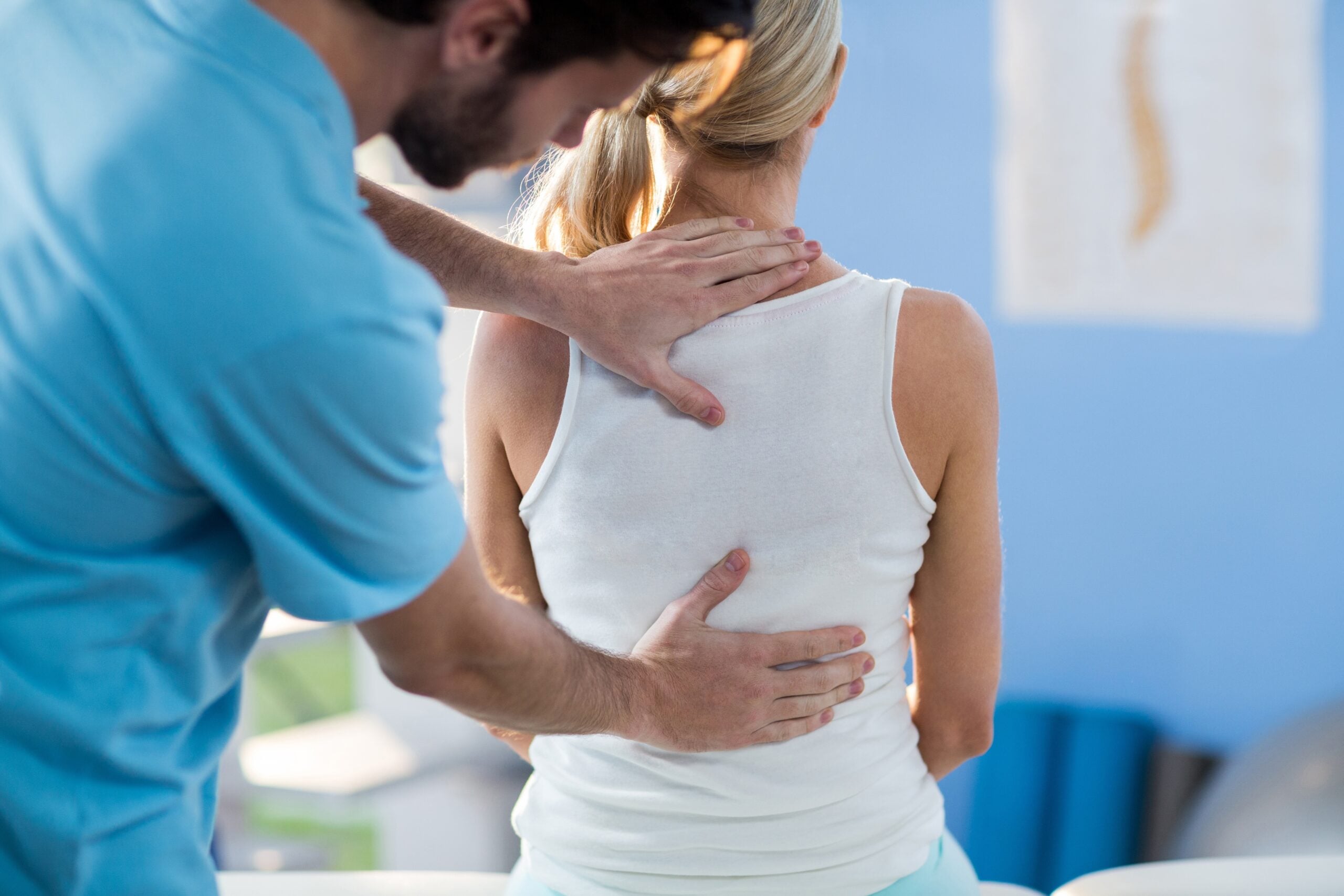 Male physical therapist giving back massage to female patient