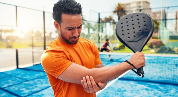 Elbow pain, padel racket and man on court with sports injury, outdoor game and sprain for inflammation. Tennis, muscle tension or athlete with joint ache from training accident, tendinitis and strain.