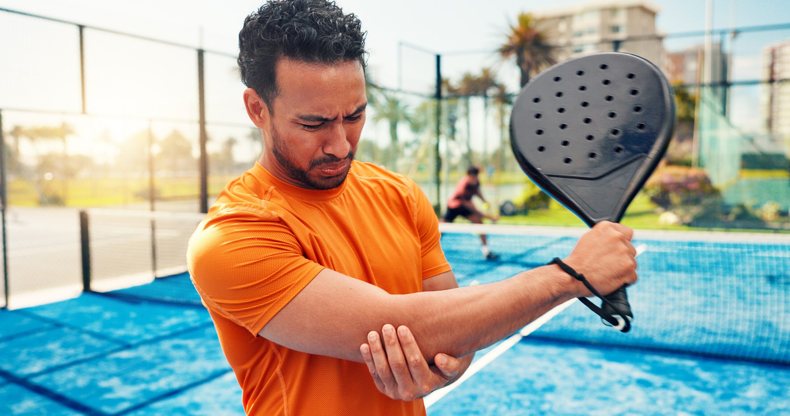 Elbow pain, padel racket and man on court with sports injury, outdoor game and sprain for inflammation. Tennis, muscle tension or athlete with joint ache from training accident, tendinitis and strain.